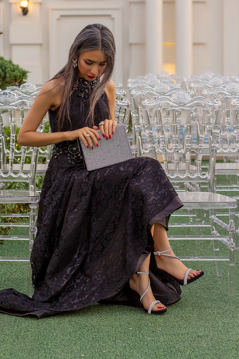 Woman in gown sits elegantly, holding a purse.